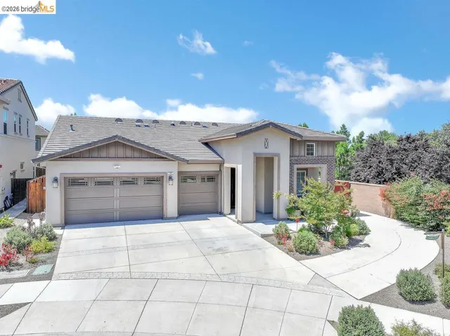 Contemporary stucco exterior with a tiled roof, featuring a two-car garage, an additional single-car garage, and a brick accent facade