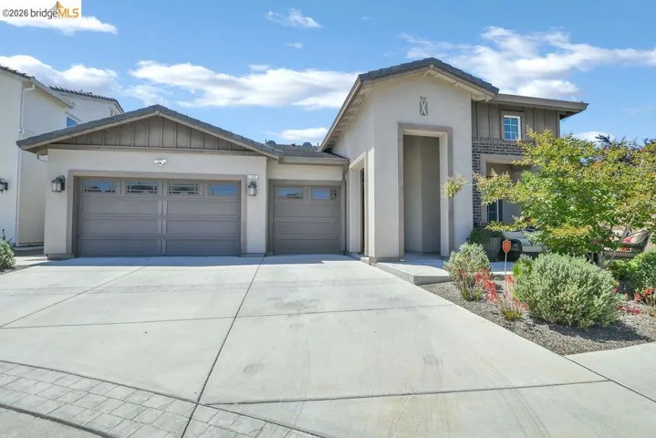 Contemporary stucco and stone-accented facade featuring an integrated two-car garage and an additional single-car garage