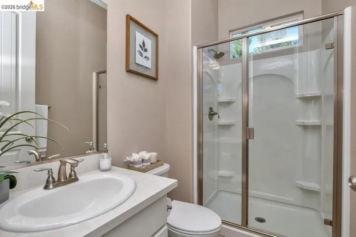 Bathroom featuring a built-in shower with glass enclosure, single vanity with integrated sink, and brushed nickel fixtures