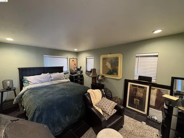 Recessed lighting illuminates this room featuring tile flooring, multiple windows with blinds, and light green walls