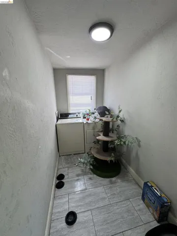 Dedicated utility space featuring a window with blinds, tile flooring, and a flush-mount ceiling light fixture