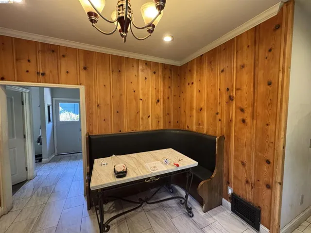 Dining area featuring knotty pine paneling, crown molding, and tiled flooring