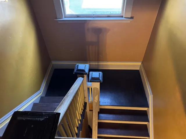 Staircase featuring dark wood treads and risers, a light-toned wood handrail, and white trim accents