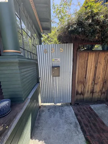 Corrugated metal gate featuring prominent address numbers and a mailbox
