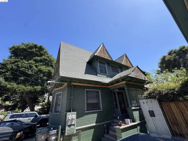 Victorian-style residence featuring a prominent gabled roof with decorative shingles, dark green siding, and a covered entry porch