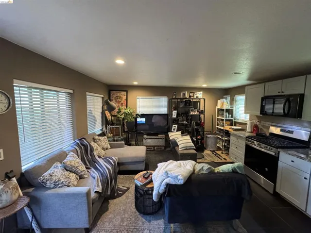 Open-concept living space featuring recessed lighting, multiple windows with blinds, and wood-finish flooring