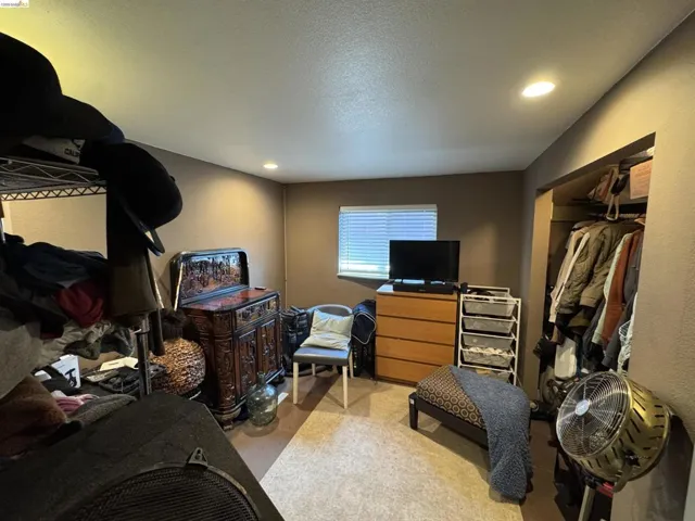 Recessed ceiling lighting illuminates the room with light brown walls and neutral-toned carpet