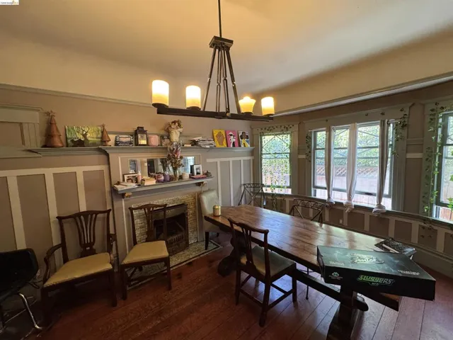 Room featuring hardwood flooring, a fireplace with a tiled surround and mantel, and wainscoting