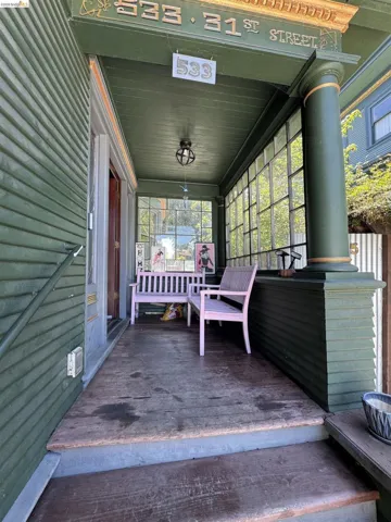 Covered front porch featuring wood flooring, a decorative overhead light fixture, and a column with gold-accented capital