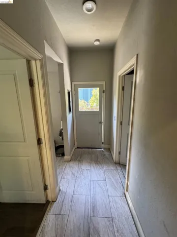 Hallway featuring wood-look tile flooring, light gray wall paint, and white trim