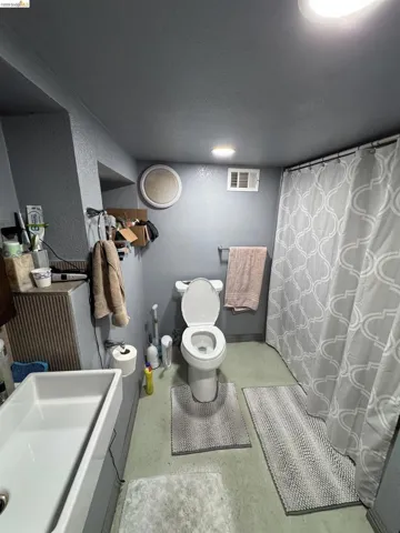 Bathroom featuring a white toilet, a white sink basin, and a shower curtain with a geometric pattern