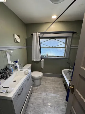 Bathroom featuring a white integrated sink vanity, white toilet, and a clawfoot tub