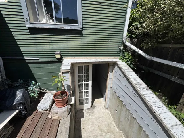 Exterior foundation access featuring a paneled wood door and concrete steps