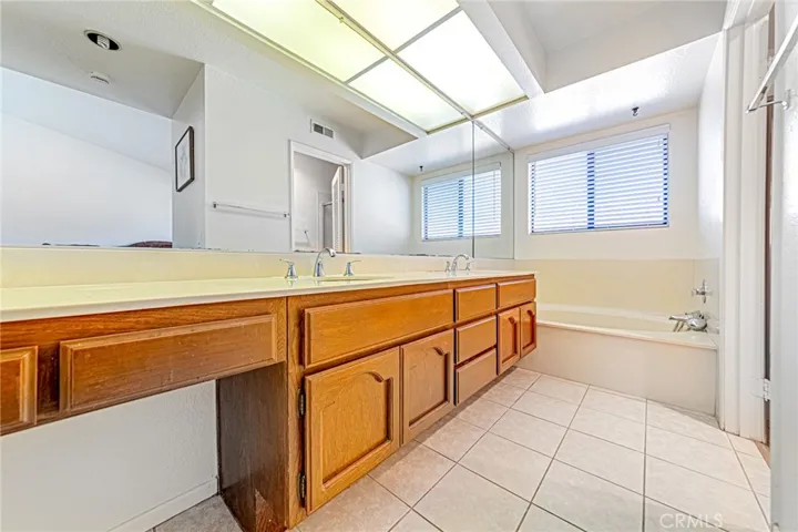 Primary bath featuring dual sinks, bathtub, and tile flooring