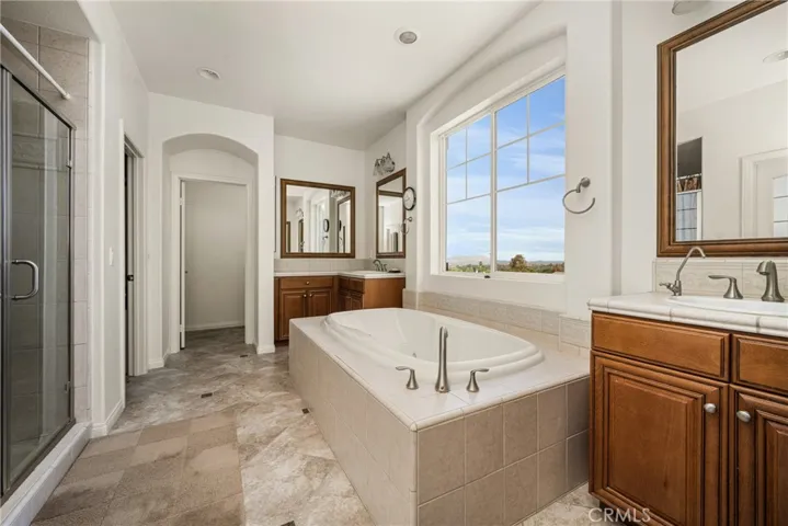 Ensuite Primary Bathroom with Dual Sinks, Separate Bathtub & Shower, and two Walk-In Closets.