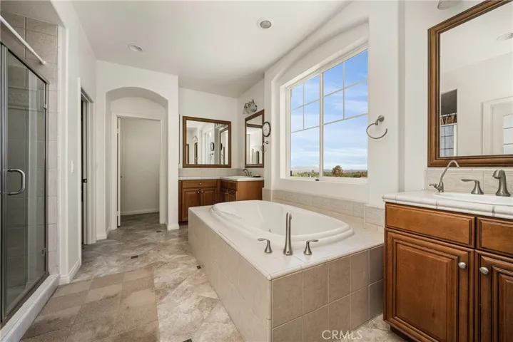 Ensuite Primary Bathroom with Dual Sinks, Separate Bathtub & Shower, and two Walk-In Closets.