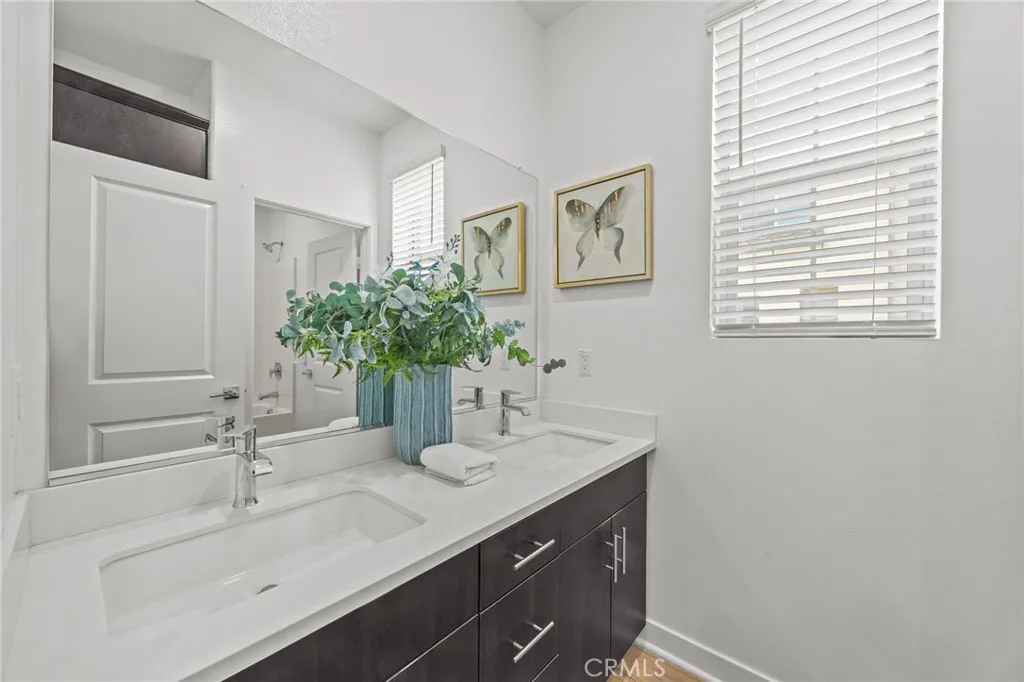 Hall bath with dual sink, linen closet and door to tub area