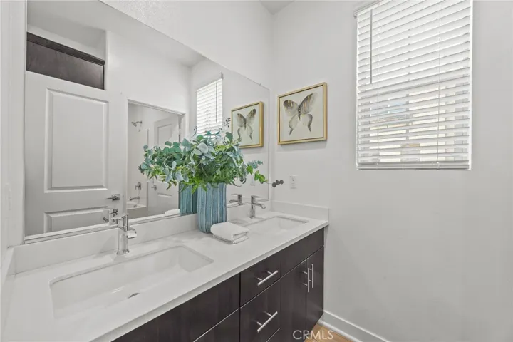 Hall bath with dual sink, linen closet and door to tub area
