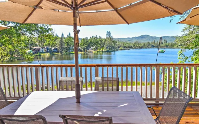 Expansive wood-finish deck featuring a full lake backdrop and distant tree-lined mountains