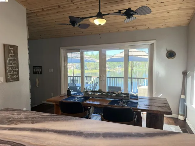 Dining area featuring a wood-panel ceiling, ceiling fan with integrated lighting, and sliding glass doors opening to an exterior deck