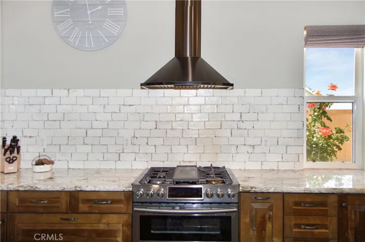 Stainless Steel Slide-in Gas Range with Griddle and Dual Convection Ovens, Attractive Hood, Stylish Tile Backsplash, Soft-Close KraftMaid Cabinetry with Custom Inserts, and Beautiful Shade