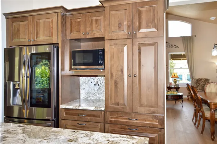 There'This Recently Remodeled Kitchen Boasts Gorgeous Slab Granite Countertops with Waterfall Edges on the Island, Soft-Close KraftMaid Cabinetry with Customized Inserts, Stainless Steel Appliances (Slide-in Gas Range with Dual Convection Ovens, Attractive Hood, and Super-Quiet Dishwasher), Stylish Tile Backsplash, Beautiful Shades, and a Dual Basin Porcelain Sink with Tree-Filled Backyard Views Atop Engineered Hardwood Floorings a Modern Farmhouse Vibe in this Recently Remodeled Kitchen which Boasts Gor...