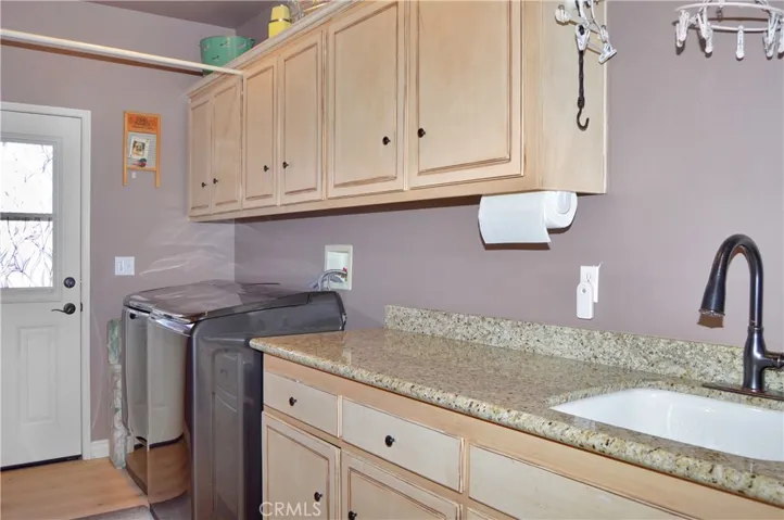 The Laundry/Utility Room is on the Main Floor and Features a Porcelain Sink, Granite Countertop, Abundant Cabinetry, Engineered Hardwood Flooring, and a Door to the Backyard.