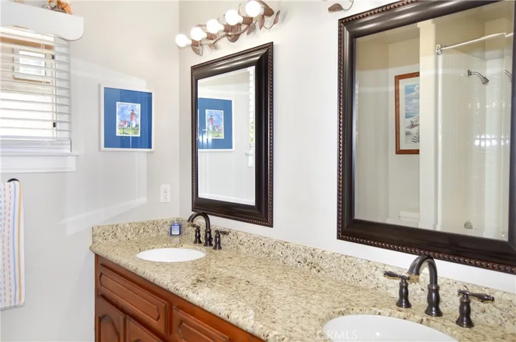 The 2nd Full Bath Boasts Dual Sinks, Granite Countertops, Framed Mirrors, Updated Lighting and Fixtures, and a Shower/Tub Combo