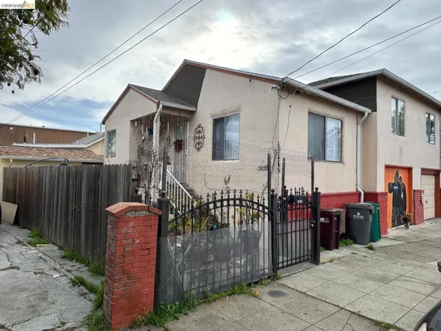 View of front of home featuring a fenced front yard, stucco siding, a gate, brick siding, and a garage