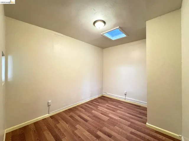 Unfurnished room with dark wood-style flooring and baseboards