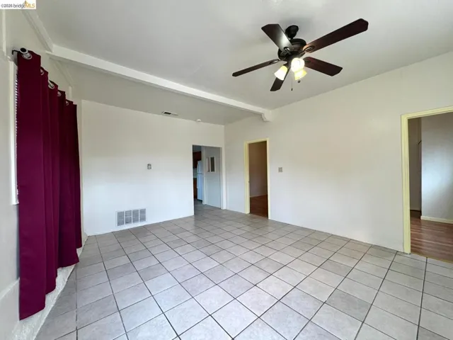 Unfurnished room featuring beam ceiling, ceiling fan, and light tile patterned floors