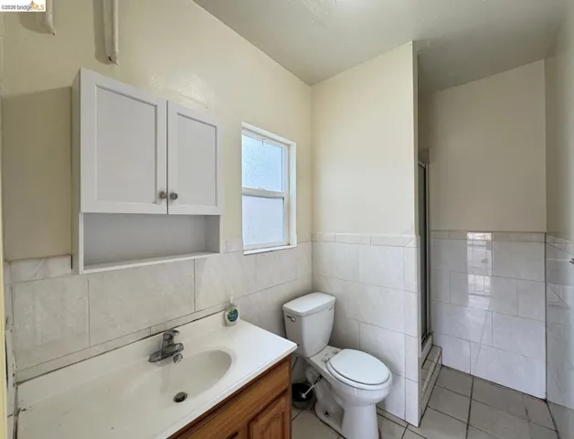 Bathroom with vanity, light tile patterned flooring, a stall shower, tile walls, and a wainscoted wall