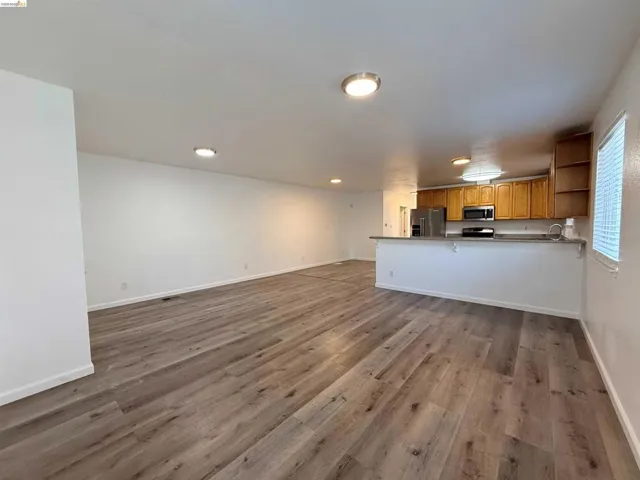 Spacious living area featuring wood-finish flooring, recessed lighting, and a neutral color palette