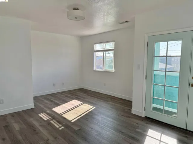Living area featuring wood-finish flooring, white baseboards, and a white ceiling with a flush-mount light fixture