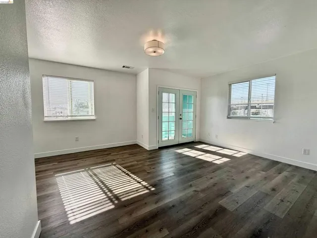 Spacious interior featuring wood-finish flooring, white walls, and a contemporary flush-mount ceiling light