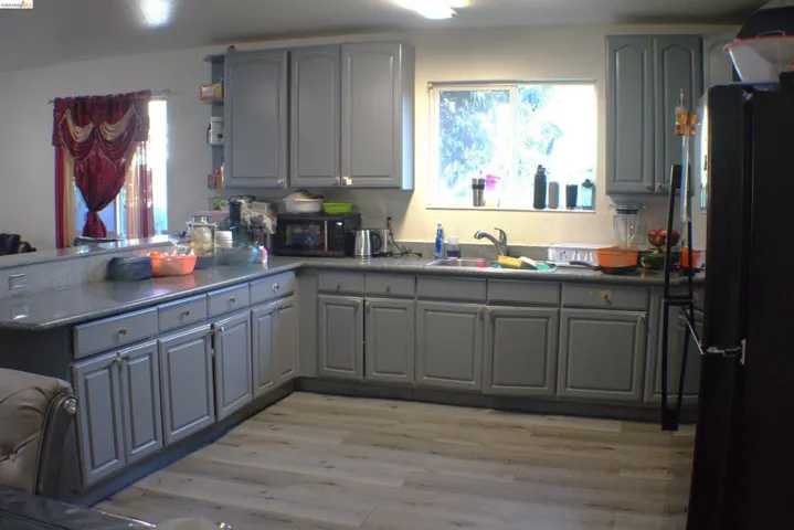 Kitchen featuring wood-finish flooring, light grey cabinetry, and dark countertops