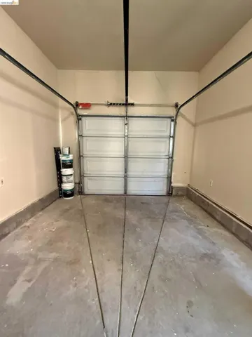 Garage space featuring a single overhead door, concrete flooring, and painted walls