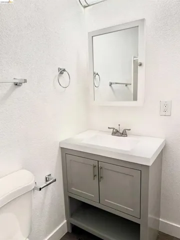 Bathroom featuring a white vanity with a gray cabinet, integrated sink, and chrome fixtures