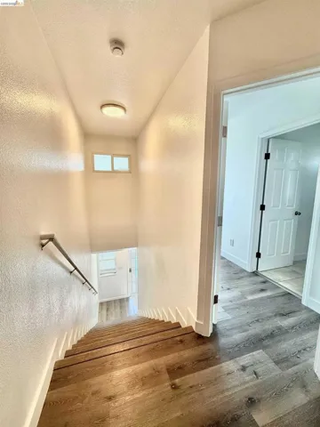 Staircase featuring wood-finish treads and a metal handrail