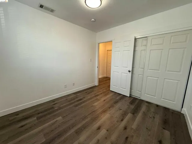 Room featuring wood-finish flooring, white baseboards, and a white ceiling with a flush-mount light fixture