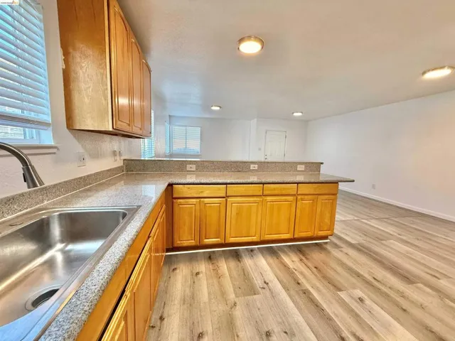 Kitchen featuring wood cabinetry, solid surface countertops, and an undermount stainless steel sink