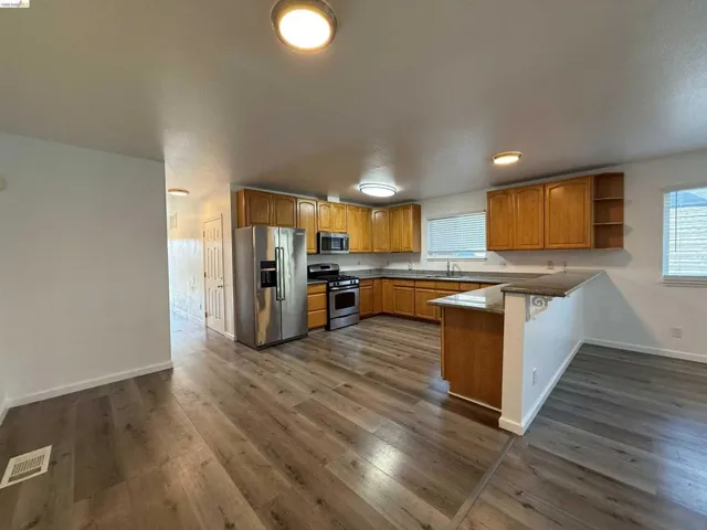 Kitchen featuring wood-finish flooring, wood cabinetry, stainless steel appliances, and a breakfast bar