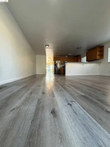Expansive room featuring wide plank wood-finish flooring, recessed lighting, and a neutral color palette