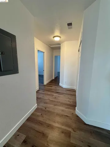 Hallway featuring wood-finish flooring, white baseboards, and a flush-mount ceiling light fixture