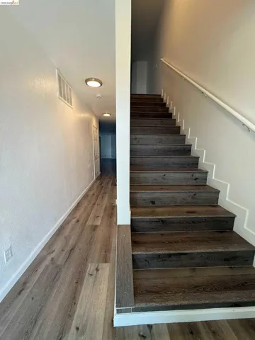 Staircase featuring wood-finish treads and a white handrail