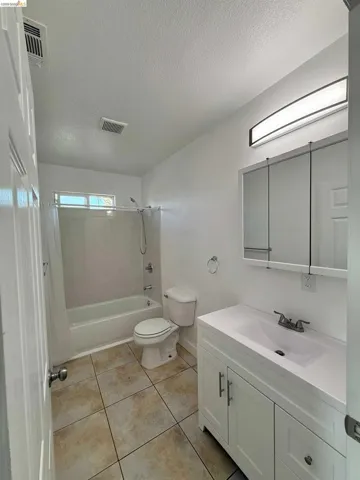 Bright bathroom featuring a white vanity with integrated sink, a rectangular mirrored medicine cabinet, and a modern linear light fixture