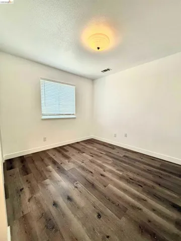Room featuring wood-finish flooring, white walls, and bright white trim