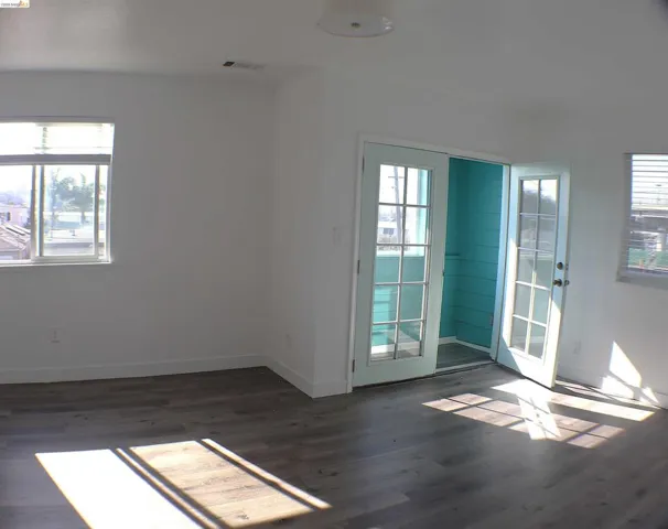 Spacious interior featuring wood-finish flooring, white walls, and a ceiling-mounted light fixture