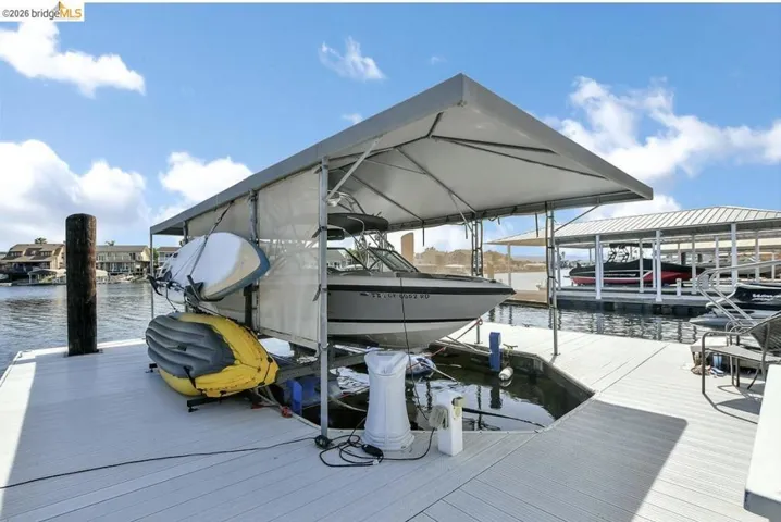 Waterfront dock with a covered boat lift, featuring composite decking and direct water access