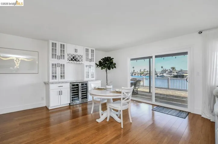 Hardwood-finish flooring leading to a sliding glass door and an outdoor deck overlooking a waterway